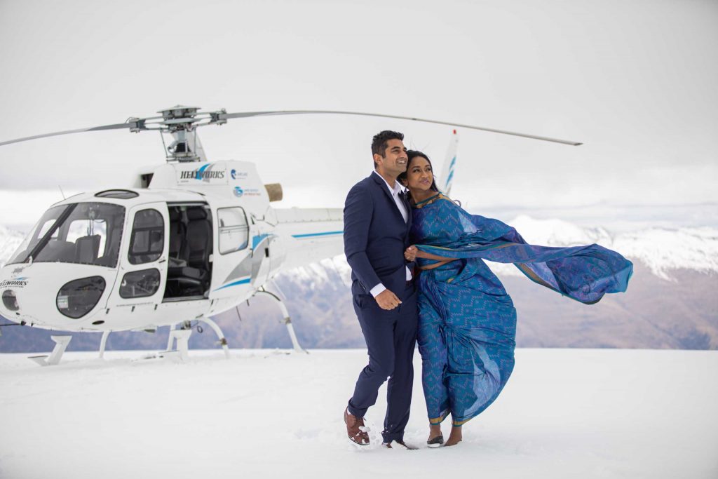 Couple on snow with helicopter in background