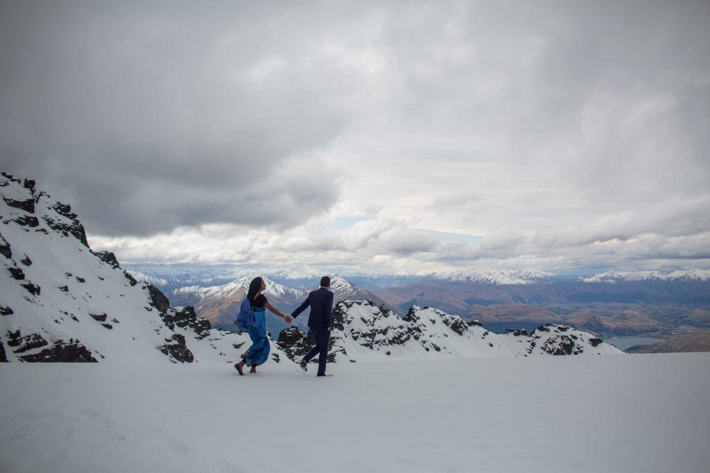 couple holding hands with mountains in background on snow