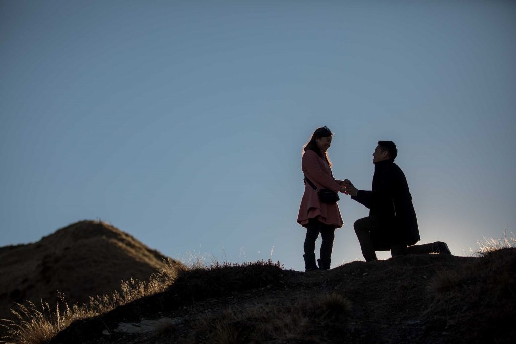 Guy proposing to girl on mountain top