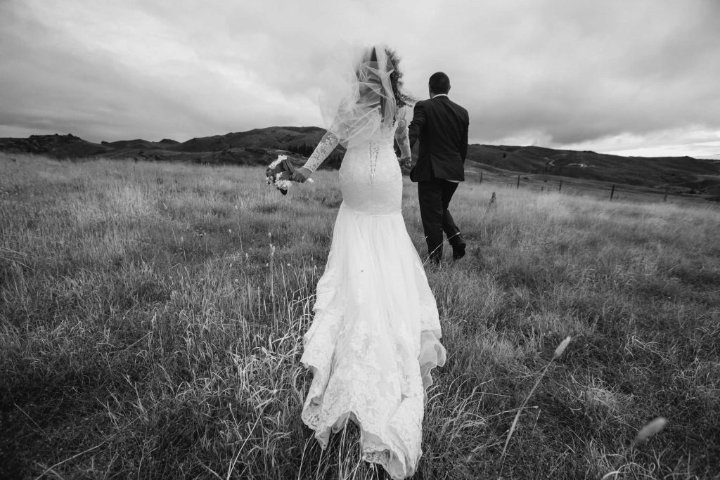 bride and groom walking over field