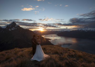 Bride and groom on mountain looking at lake