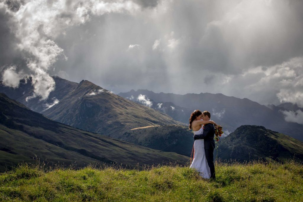 bride and groom hugging in field