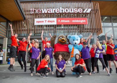 staff portrait in front of store with mascott