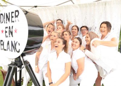 Big group in white clothes taking photo in photo booth