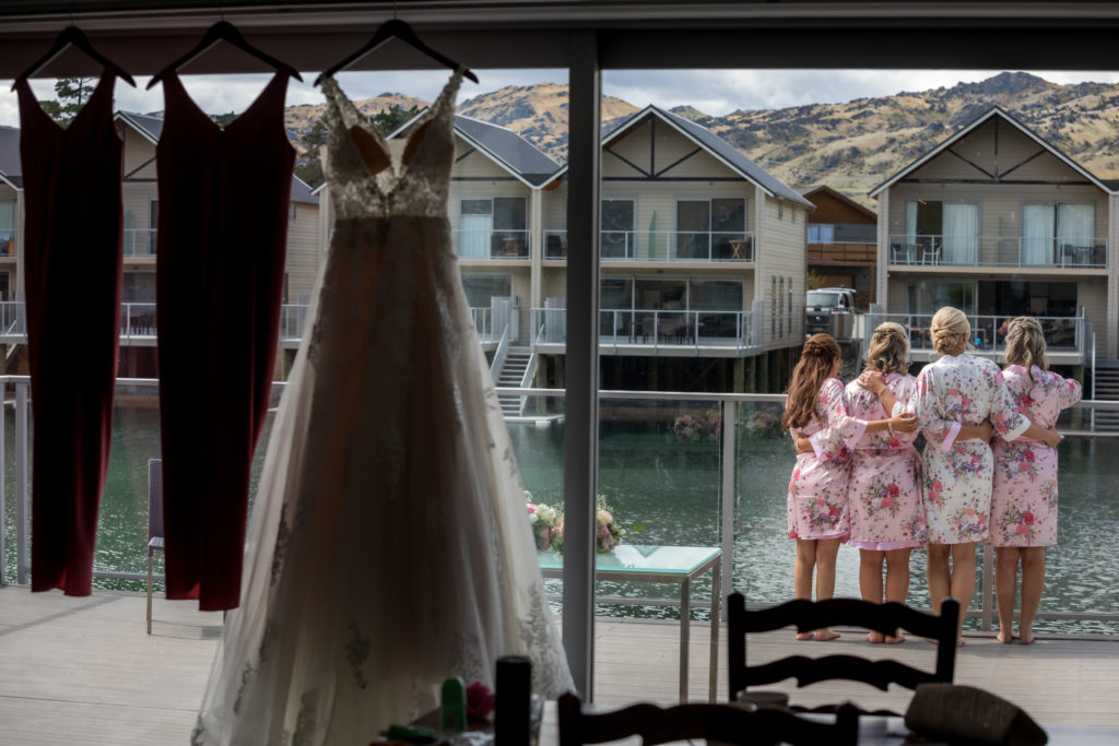 Wedding dress hung up and bridal girls in the background