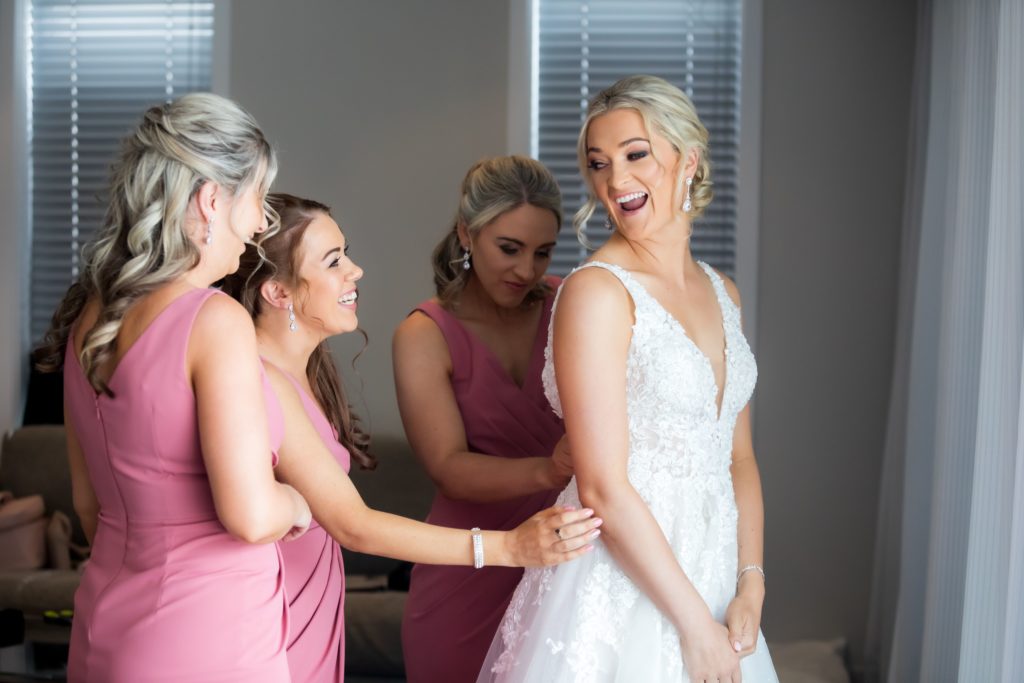 Bridesmaids getting the bride ready in her dress