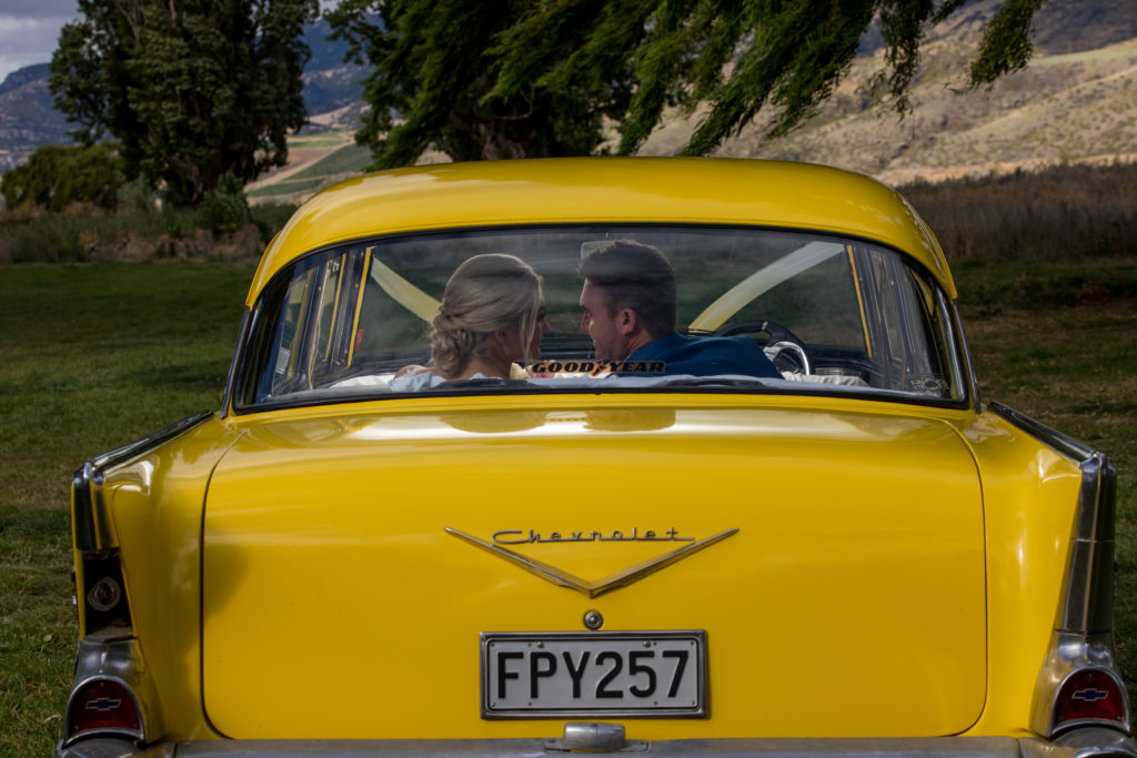 Bride and groom looking at each other in the back of a yellow car