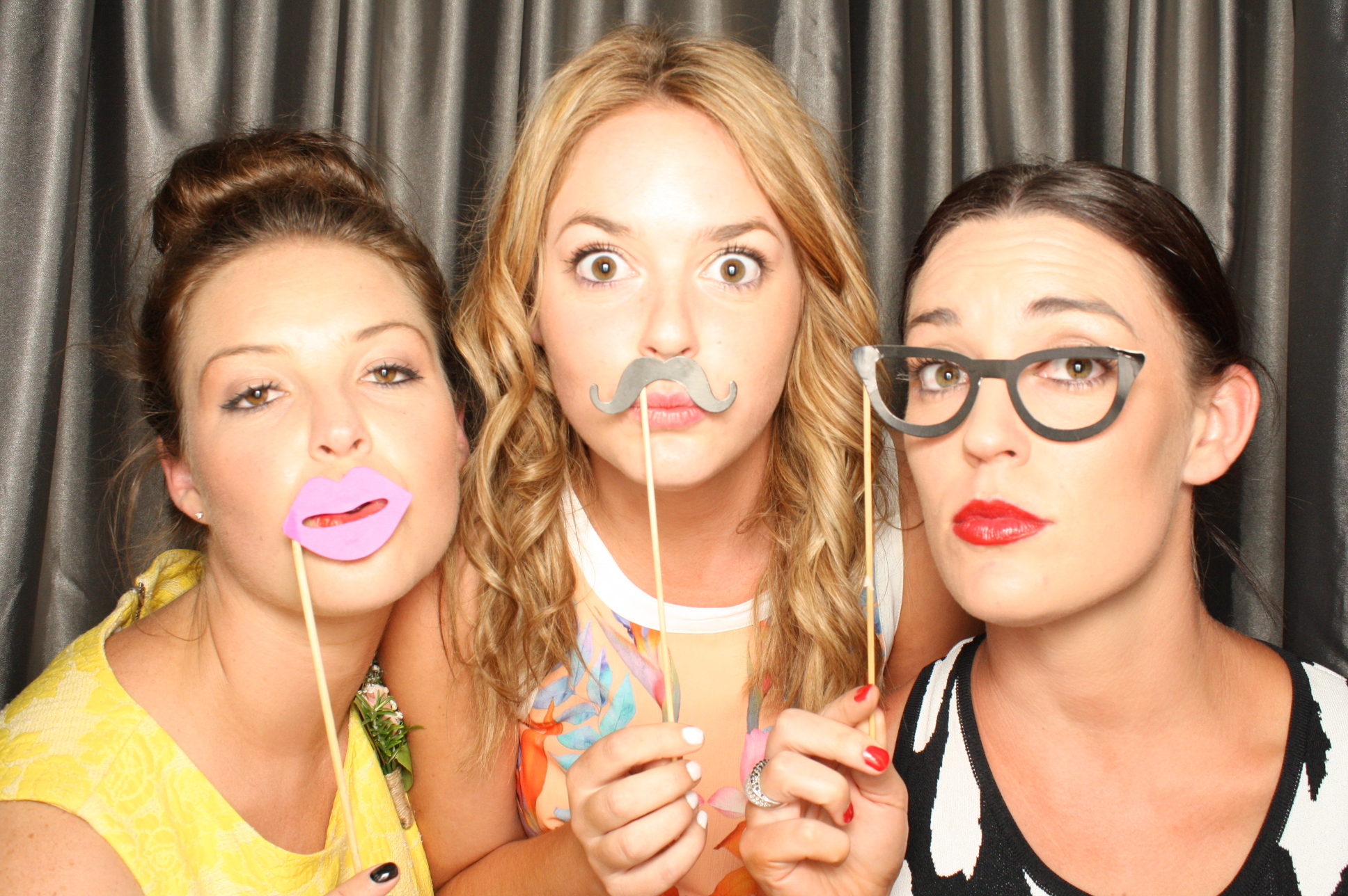 3 woman with props in photobooth