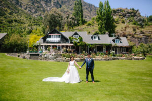 Bride and groom standing in front of a house holding hands