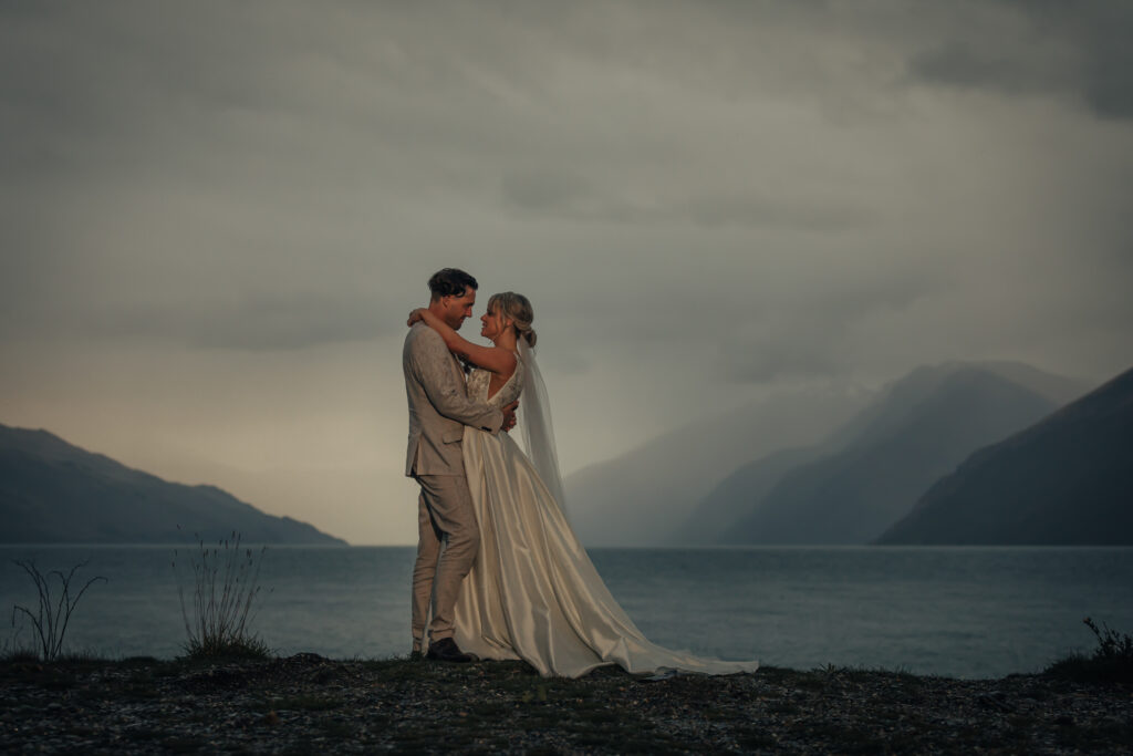 Bride and groom hugging in front of lake