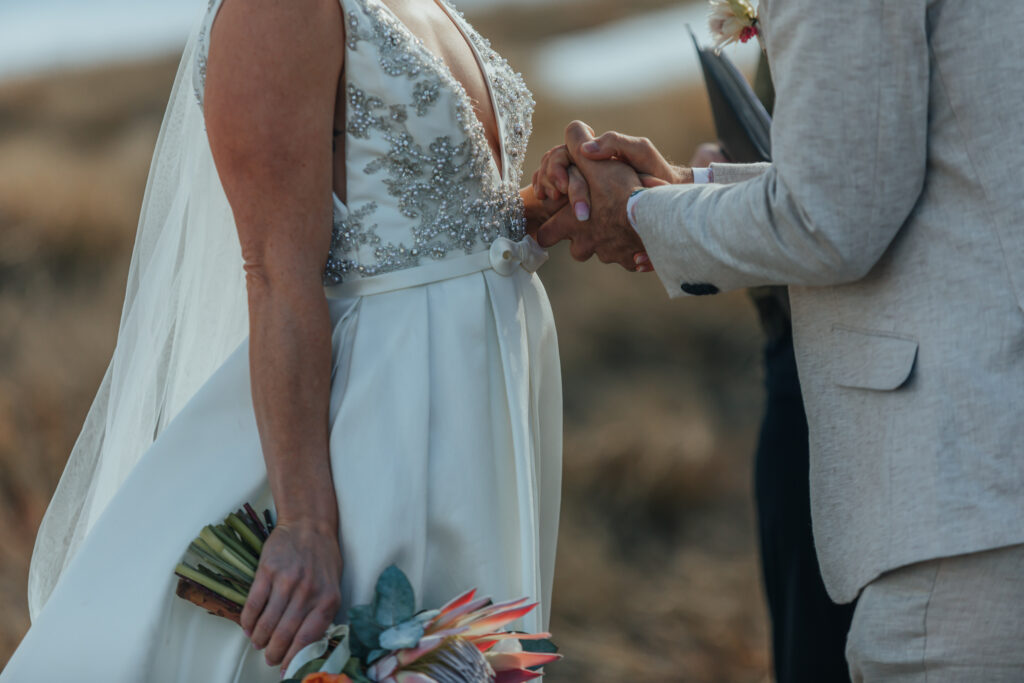 close up of groom holding bride's hand