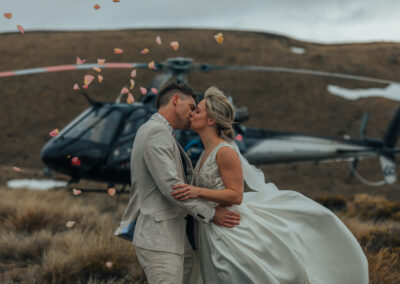 Bride and groom kissing in front of helicopter