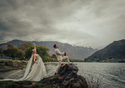 Groom popping champagne with bride behind