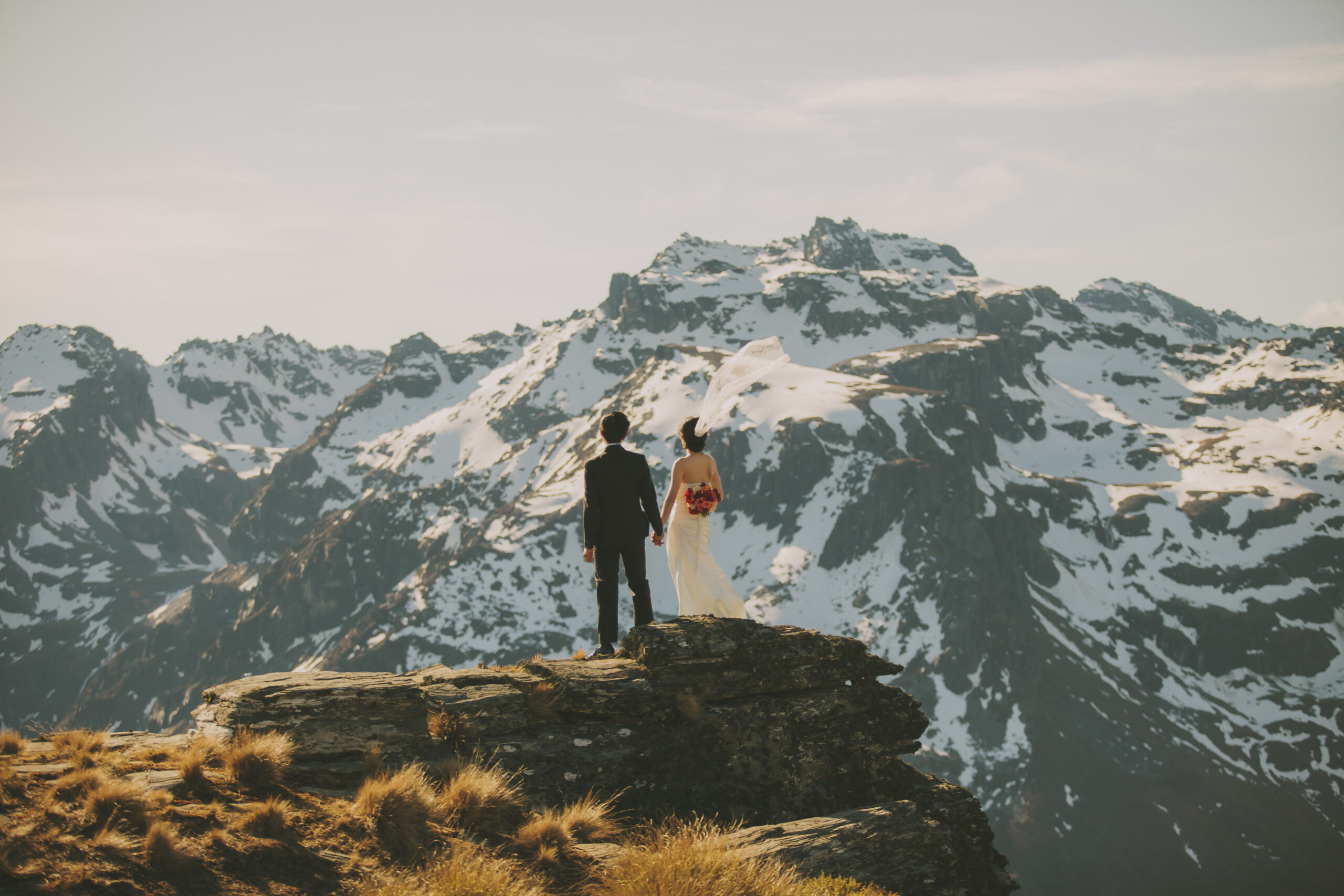 bride and groom on mountain holding hands