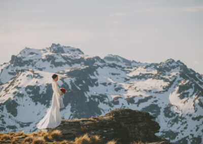 Bride on rock with snowy mountain behind