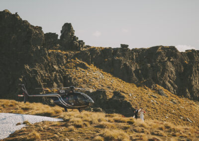 Bride and groom walking away from Helicopter on mountain