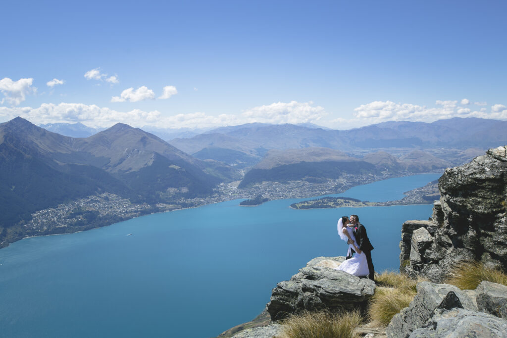 Bride and groom kissing in front on Mountain with lake views