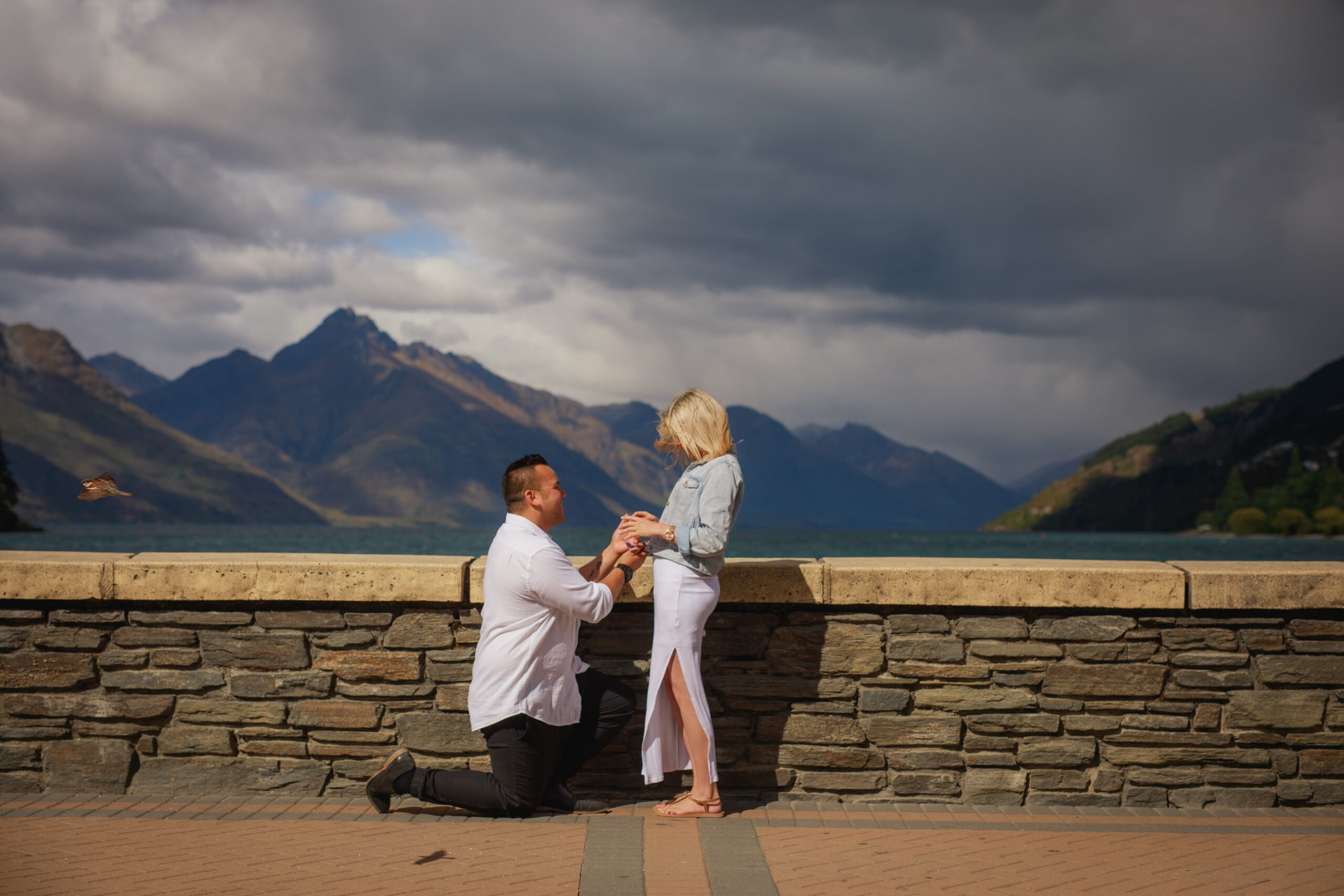 man on one knee proposing by lake