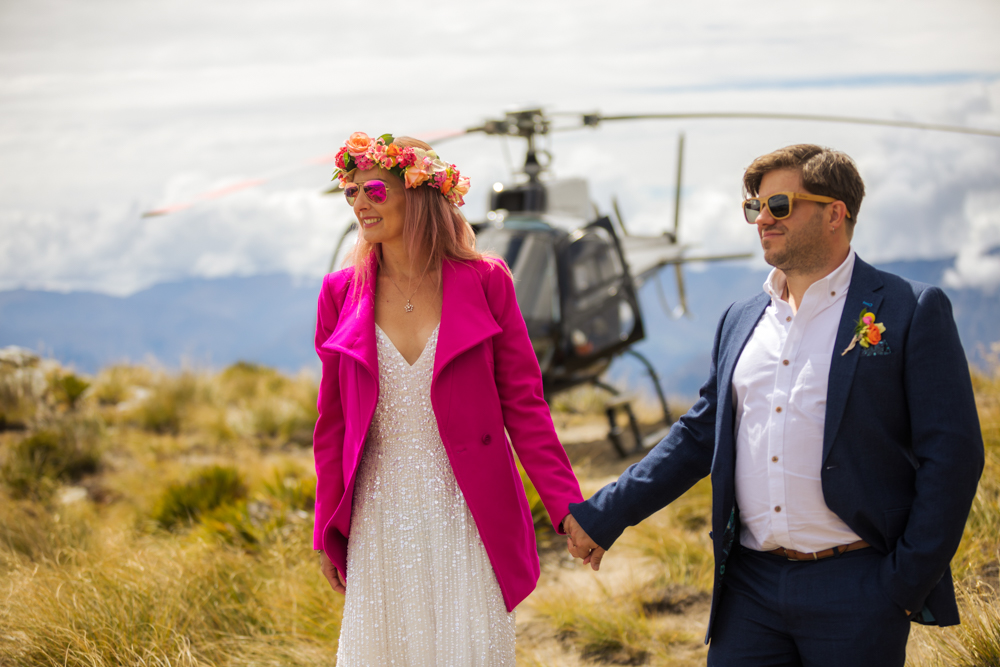 Bride and groom in front of helicopter on mountain