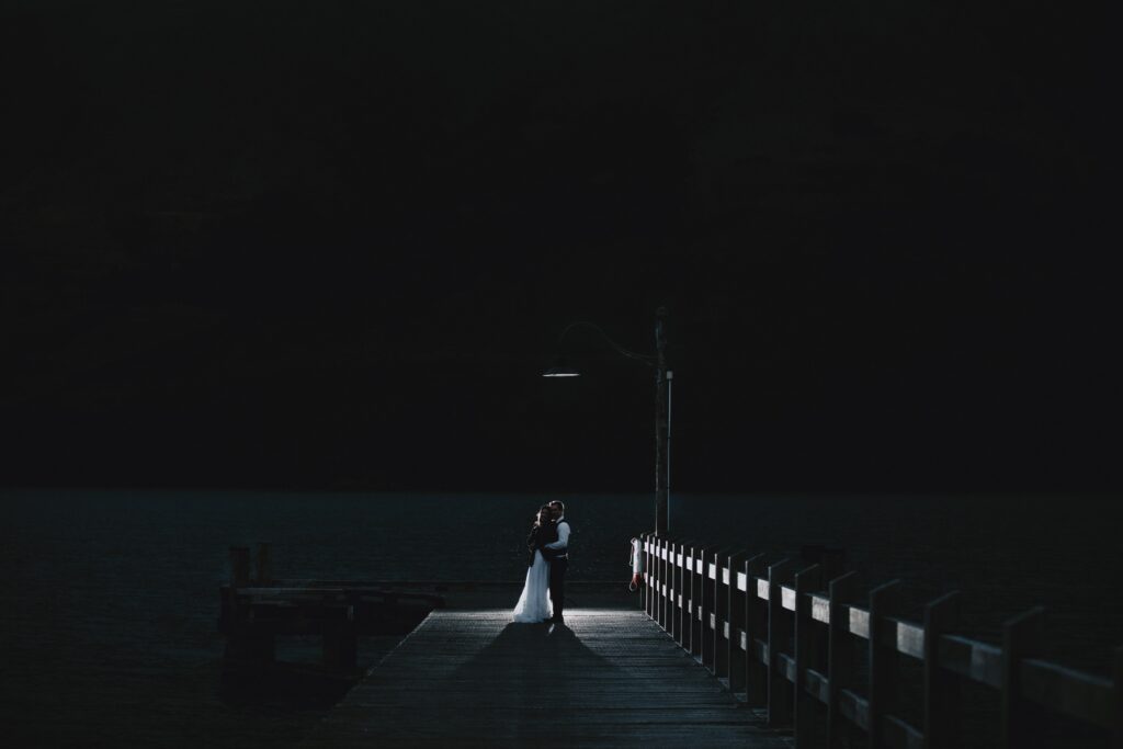 bride and groom on pier at night